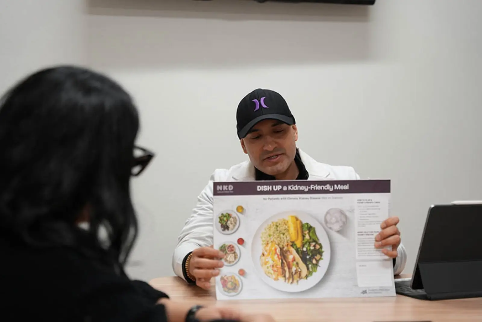 Daniel Chavez, RD, reviewing a kidney-friendly meal guide with a client at KM Wellness Center in El Paso