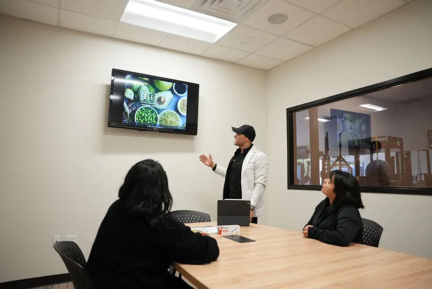 Registered dietitian explaining a nutrition plan to clients at KM Wellness Center in El Paso